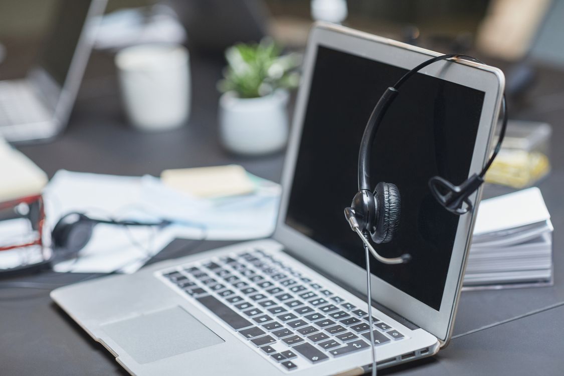 Headset resting on a laptop beside working documents