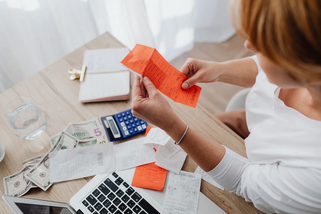 Person sorting receipts beside a laptop and calculator
